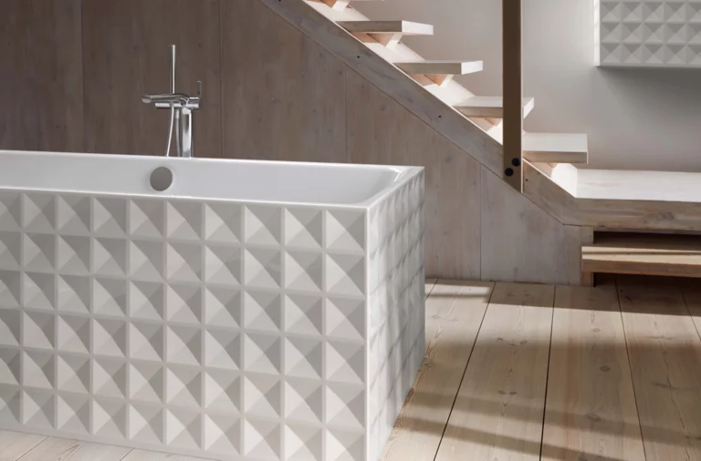 Baignoire rectangulaire autoportante en acier émaillé avec côtés extérieurs à motifs géométriques sur parquet clair.